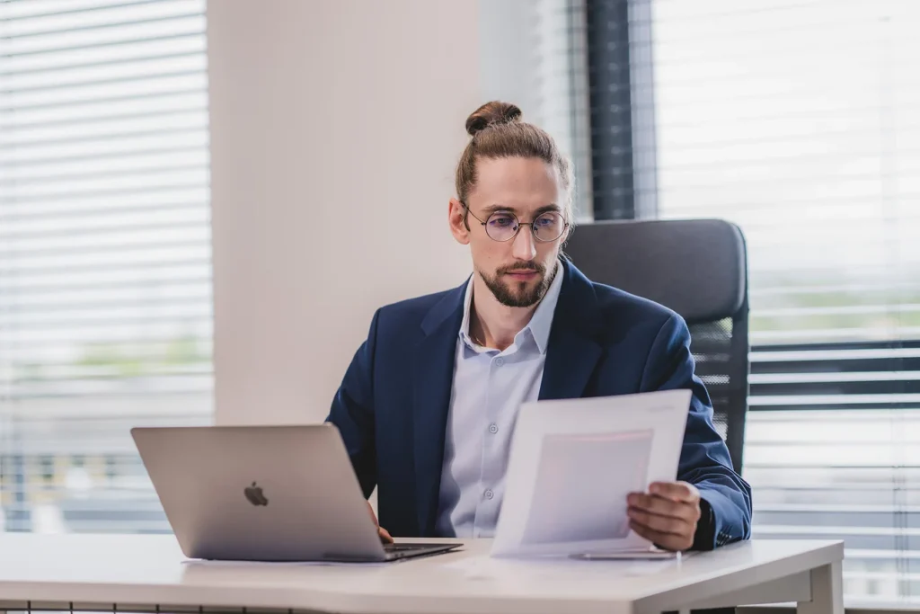 Copywriter czyta wydruk tekstu przy laptopie